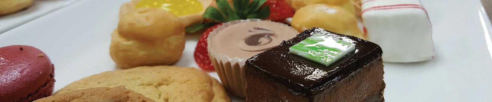 Assorted small desserts on plate. Brownies, cholocolates, strawberries, and macaroons.